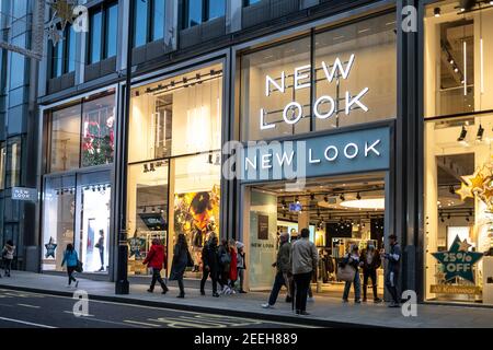 Abbigliamento nuovo look moderno centro città negozio con marchio logo e segno illuminato di notte occupato con i turisti e. acquirenti Foto Stock