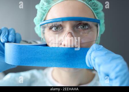 Donna medico sigilla la bocca con nastro blu Foto Stock
