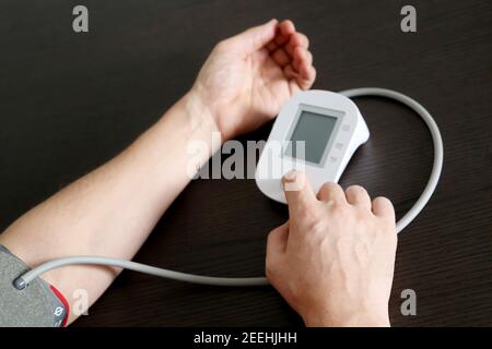 Mani maschili con monitor della pressione sanguigna, uomo che misura la pressione. Concetto di salute e cardiologia Foto Stock