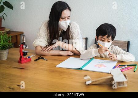 Insegnante asiatico e bambino che indossa maschere facciali di protezione in classe Durante l'epidemia di coronavirus - Focus sul viso del ragazzo Foto Stock