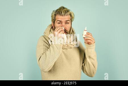 Il naso che cola e altri sintomi di raffreddore. Il coronavirus dalla cina. L'uomo usa medicinali efficaci. L'uomo tiene gocce nasali. Aiuta. Influenza concetto. Hippster si sente male starnuti. Spray nasale efficace. Foto Stock