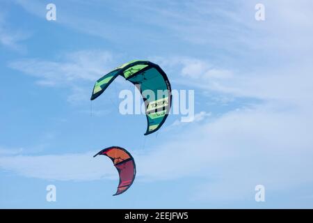 Due vele colorate per il kitesurf volano nel cielo nuvoloso. Mar dei Caraibi, Messico Foto Stock