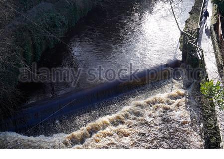 Edimburgo, Scozia, Regno Unito. 16 Feb 2021. La neve si fonde su un'acqua fluente veloce di Leith con molte strane e cascate traboccanti di acqua bianca turbolenta e la passerella impassabile in luoghi che richiedono una deviazione. BirdsEye vista di una cascata veloce che scorre. Credit: Craig Brown/Alamy Live News Foto Stock