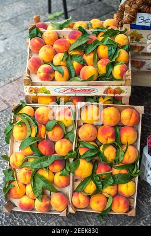 Pesche fresche, coltivate a livello regionale ed esposte in scatole presso i coltivatori di Cattaro mercato, all'aperto durante il giorno, si spera allettante passeggeri di visitare crui Foto Stock