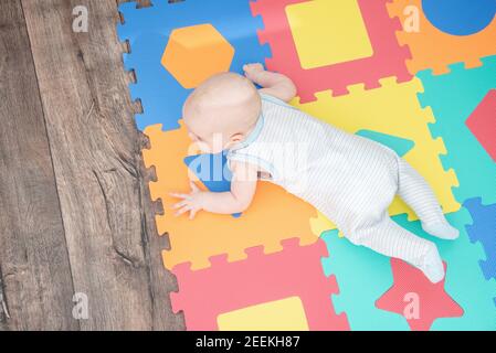 Ridendo bambino su un puzzle colorato tappetino di gomma per giocare schiuma eva con figure geometriche Foto Stock