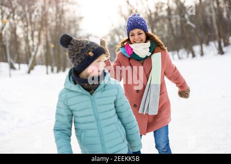 Madre e bambino che hanno combattuto con la palla di neve nel parco invernale Foto Stock