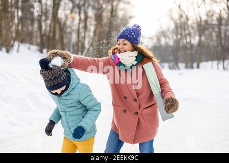 Madre e bambino che hanno combattuto con la palla di neve nel parco invernale Foto Stock