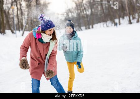 Madre e bambino che hanno combattuto con la palla di neve nel parco invernale Foto Stock