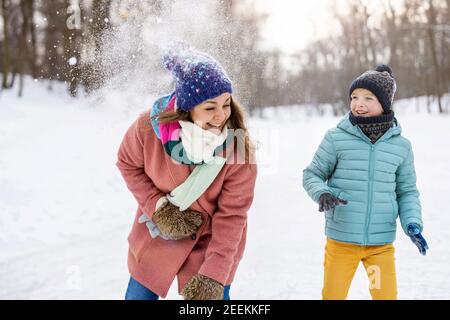 Madre e bambino che hanno combattuto con la palla di neve nel parco invernale Foto Stock