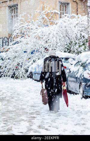 Vecchia signora che cammina con attenzione durante la nevicata nella città di Atene, capitale della Grecia, Europa Foto Stock