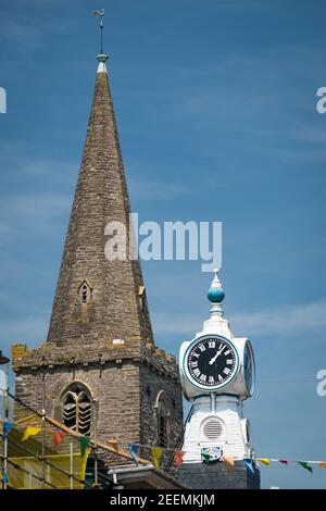 La guglia della chiesa di St Thomas Dodbrooke e St Edmund, e l'orologio sul Kings Cinema, Fore Street, Kingsbridge, Devon, Regno Unito. Foto Stock