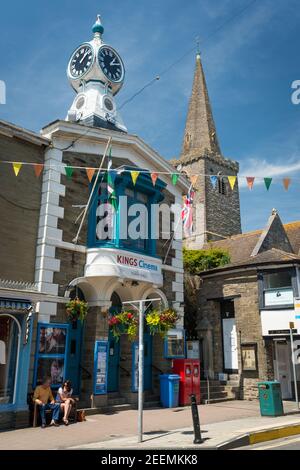 La guglia della chiesa di St Thomas Dodbrooke e St Edmund, e l'orologio sul Kings Cinema, Fore Street, Kingsbridge, Devon, Regno Unito. Foto Stock