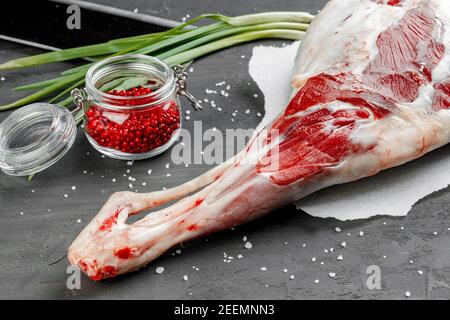 Gamba di agnello crudo su fondo di pietra nera Foto Stock