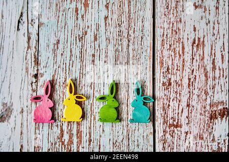 Quattro coniglietti pasquali colorati su un tavolo di legno. Foto Stock