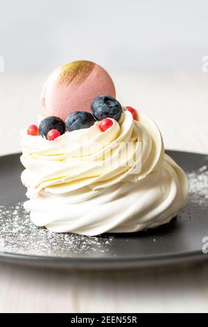 Primo piano torta Meringue Pavlova con mirtillo e mini Macaron Foto Stock