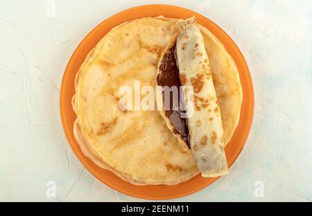Guarnite con un pancake con cioccolato alle nocciole spalmato. Vista dall'alto di una pila di pancake. Foto Stock