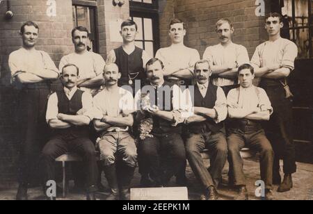 Cartolina fotografica d'epoca dei primi del XX secolo con un gruppo di uomini e un Cat. L'accesso davanti agli uomini sembra dire Whitehall sta???. Forse un gruppo di poliziotti. Foto Stock