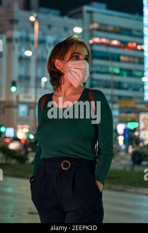 Ritratto di una giovane donna che indossa una maschera nel città di notte Foto Stock