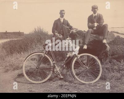 Fotografia edoardiana d'epoca del 1904 che mostra due uomini adatti che riposano accanto a un ciclo a pedale. Forse a Norfolk. Foto Stock