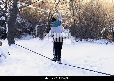 Un giovane adolescente equilibra un tightrope nella neve Foto Stock