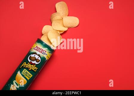 Lattina di formaggio Pringles e cipolla. Cartone con patatine Pringles su sfondo rosso Foto Stock