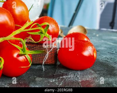 Piccole gocce d'acqua sui pomodori ciliegini sul ramo verde Foto Stock