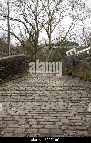 L'Old Stone Bridge adiacente al Lock 23E sul canale stretto di Huddersfield nel villaggio di Slaithwaite, West Yorkshire, Inghilterra Foto Stock