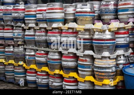 Numerose botti di birra in metallo con anelli di identificazione colorati accatastati fuori dall'azienda di produzione Empire Brewing, a Slaithwaite, West Yorkshire. Foto Stock