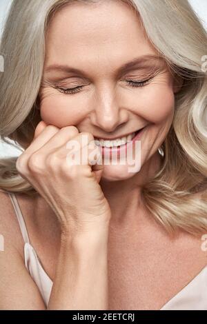 Felice cute timida donna di mezza età ridendo. Anti AGE cura della pelle del viso, vista closeup Foto Stock