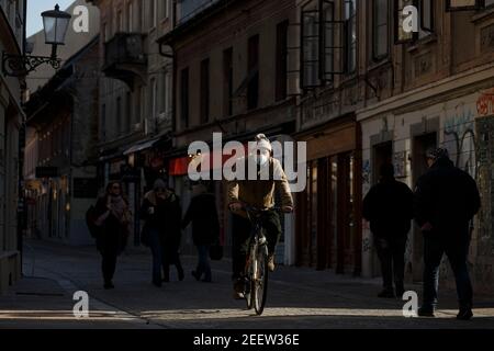 Lubiana, Slovenia. 16 Feb 2021. Un uomo che indossa una maschera facciale fa un giro in bicicletta a Lubiana, Slovenia, il 16 febbraio 2021. La Slovenia ha segnalato martedì 740 nuovi casi COVID-19 nelle ultime 24 ore, portando il bilancio nazionale a 180,507. Credit: Zeljko Stevanic/Xinhua/Alamy Live News Foto Stock