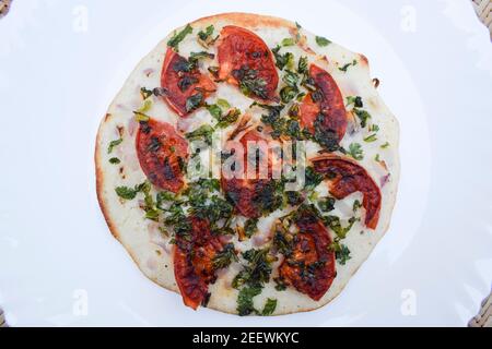 L'Uttapam, conosciuto anche come Uttapa, è un pancake indiano saporito. Condimento di pomodoro, coriandolo e cipolla a fette. Questo è l'uttapam di pomodoro Foto Stock