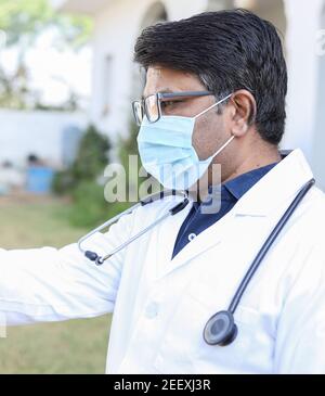 Medico indiano di mezza età che indossa una maschera facciale con un estensibile mano Foto Stock