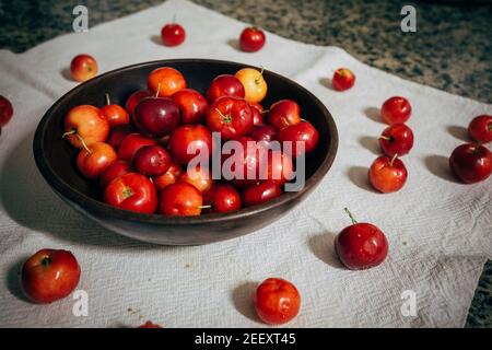 Ciliegia di Acerola (Malpighia emarginata) frutta tropicale, cruda, fresca in ciotola di legno. È noto per essere estremamente ricco di vitamina C e antiossidante Foto Stock