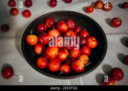 Ciliegia di Acerola (Malpighia emarginata) frutta tropicale, cruda, fresca in ciotola di legno. È noto per essere estremamente ricco di vitamina C e antiossidante Foto Stock