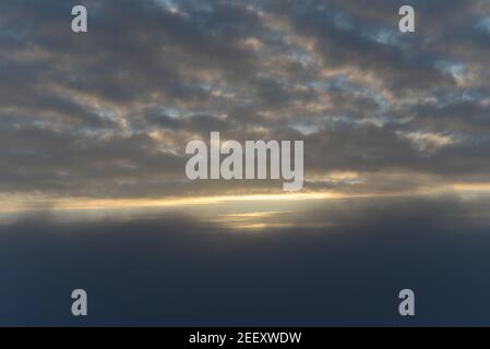 Cielo tardo autunno con nuvole, nebbia fitta e il sole che si infrange parzialmente attraverso le nuvole. Foto Stock