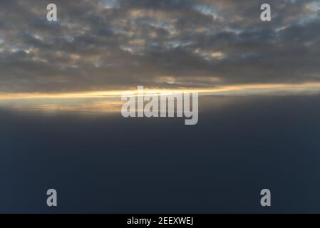 Cielo tardo autunno con nuvole, nebbia fitta e il sole che si infrange parzialmente attraverso le nuvole. Foto Stock