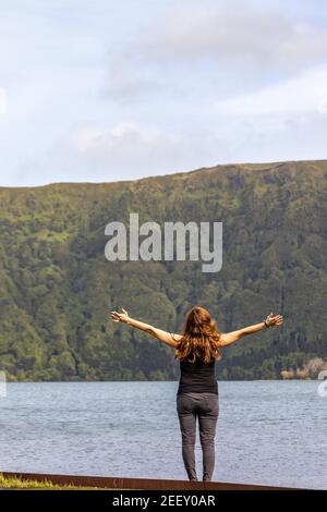 Donna con le braccia aperte, abbracciando il mondo, Sete Cidades paesaggio, viaggio Azzorre. Foto Stock