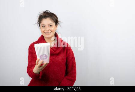 Giovane ragazza in maglione che mostra un secchio di popcorn Foto Stock