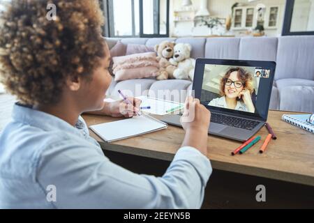 Giovane insegnante di sesso femminile che ha lezioni online con la studentessa tramite l'app di chat video durante il blocco. Messa a fuoco sullo schermo del laptop Foto Stock