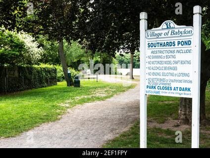 Babylon, New York, USA - 15 Giugno 2018: Guardando l'ingresso di Southards Pond con Babylon Villeges regole per il lago postato su un cartello. Foto Stock