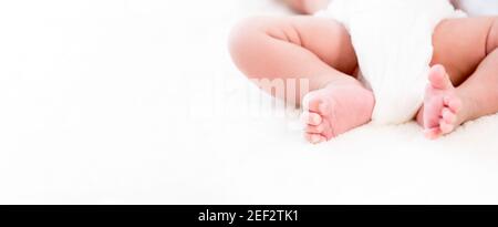 Gambe e piedi del bambino su foglio di lanugine bianco - banner web panoramico con spazio per la copia Foto Stock