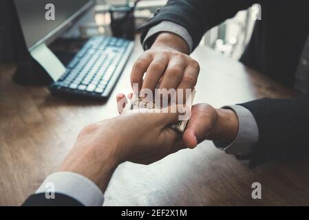 Uomo d'affari che mette i soldi nella sua mano del socio - corruzione e. concetti di corruzione Foto Stock