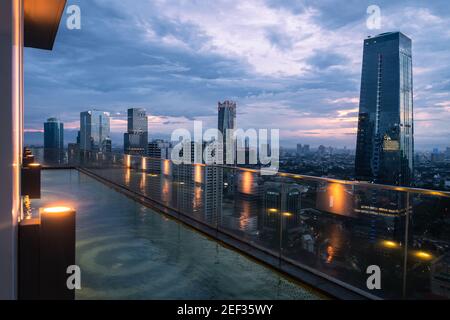 Giacarta, Indonesia - 3 novembre 2019: Il sole tramonta sullo skyline di Giacarta dalla piscina di un'alta torre condominiale nella capitale indonesiana. Foto Stock