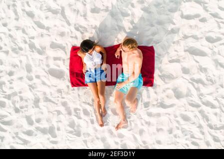 Vista dall'alto di una coppia adagiata sulla spiaggia di sabbia bianca un bagno di sole in vacanza estiva Foto Stock