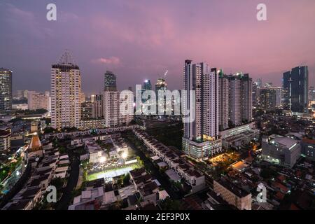 Tramonto sullo skyline di Giacarta, dove le torri e le case residenziali contrastano Con moderni edifici di uffici a Giava nella capitale indonesiana Foto Stock