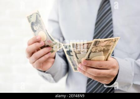 Businessman contando denaro, banconote giapponesi yen Foto Stock