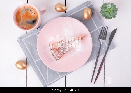 Un pezzo di torta su un piatto rosa con un coltello e forchetta su un tovagliolo di lino piegato Foto Stock