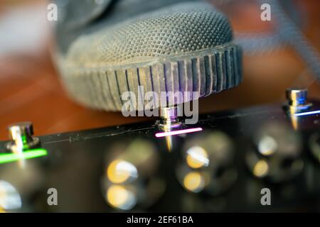 Chitarrista premendo il tasto del pedale dell'effetto chitarra con il piede Foto Stock