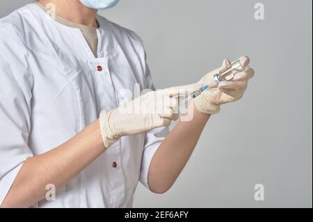 Un infermiere che prende il medicinale in una siringa da vicino a un flacone. Preparazione del vaccino del coronavirus-Covid-19. Foto Stock