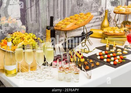 Deliziosi dessert sul tavolo da banchetto. Frutta, cocktail, vino, gelato con marmellata, biscotti con panna. Foto Stock